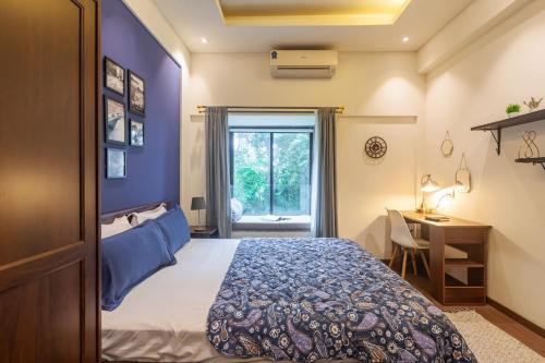 a bedroom with a bed and a desk and a window at Deshco Oasis Suites, Alibaug in Chorondpāda