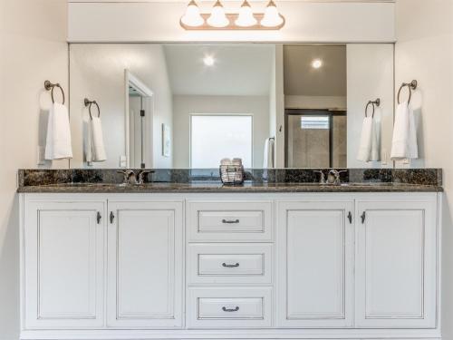 a bathroom with white cabinets and a large mirror at Unpack and Unwind in Yukon