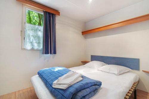 a bedroom with a bed with a blue blanket on it at 22.Mobil-home option clim 5pers in Calviac