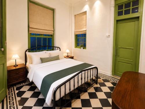 a bedroom with a bed with green doors and a table at Arvena Living in Jelutong