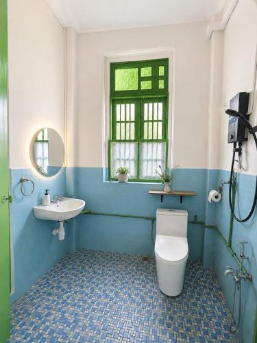 a bathroom with a toilet and a sink and a window at Arvena Living in Jelutong