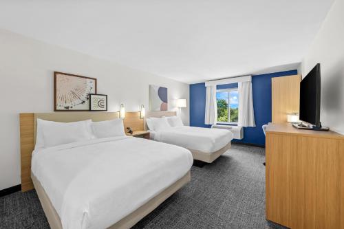 a hotel room with two beds and a flat screen tv at Spark by Hilton Milford Boston in Milford