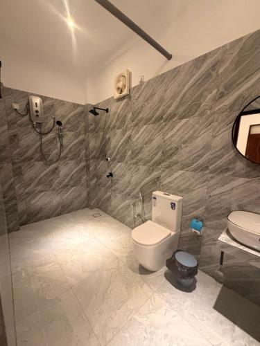a bathroom with a toilet and a shower and a sink at Blue Wings Arugam Bay in Arugam Bay