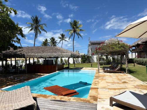 a swimming pool in a yard with palm trees at Pousada Casa Caju Bangalows in Cumbuco