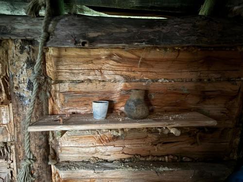 a shelf in a log cabin with a vase and a cup at Osada Słowiańska in Chyrowa