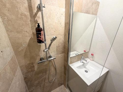 a bathroom with a shower with a sink and a mirror at Horizon Doré Appt avec piscine - vue sur mer in Gourbeyre