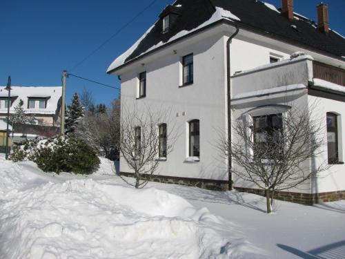 a white house with snow in front of it at Reiterhof & Pension Lienemann in Grünbach