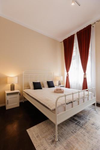 a white bed in a bedroom with red curtains at #Artistic Flat 2BR Historical Center Timișoara in Timişoara