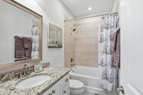 a bathroom with a sink and a tub and a toilet at Garden Cottage 89 in Jekyll Island