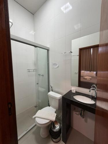 a bathroom with a toilet and a shower and a sink at Him Hotel in Iraí de Minas
