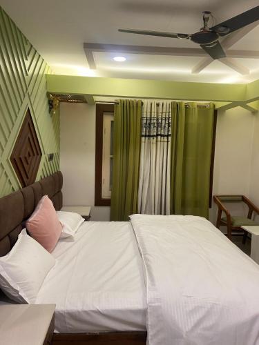 a bedroom with a white bed with a ceiling fan at Vakil Villa in Srinagar