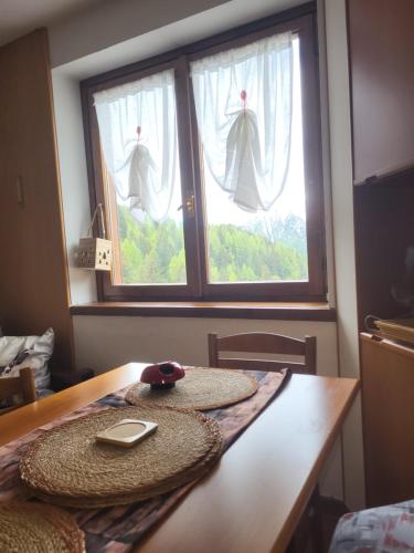 a table with a hat on it in front of two windows at Casa Bella Vista in Foppolo
