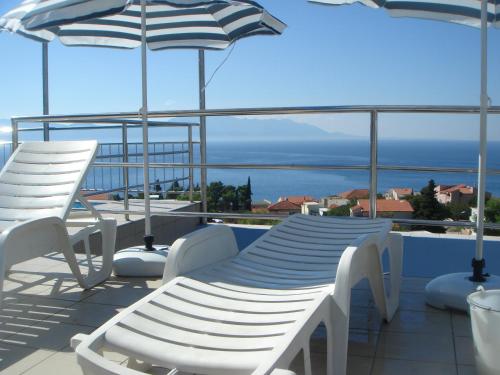 a balcony with chairs and tables and umbrellas at Aparthotel Pecic in Gradac