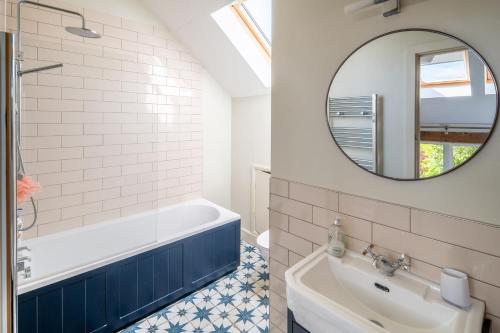 a bathroom with a tub and a sink and a mirror at Wolmers Barn in Stonham Aspall