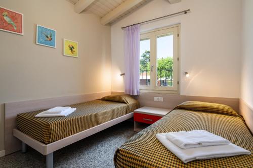 two beds in a room with a window at Onda Blu Resort in Manerba del Garda