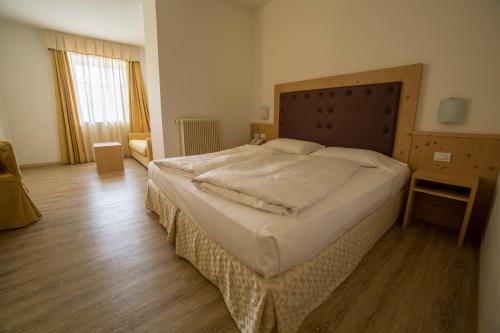 a bedroom with a large bed with a wooden headboard at Alpen Hotel Eghel in Folgaria