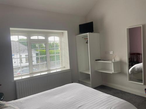a white bedroom with a bed and a window at Slievebawn Accommodation in Sligo