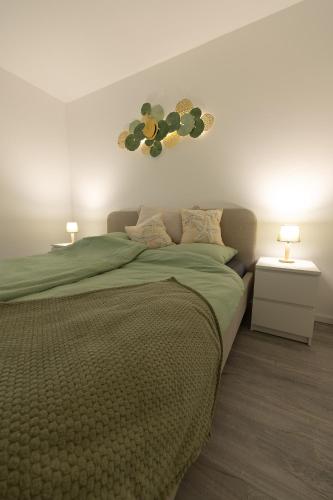 a bedroom with a bed with a green comforter and two lamps at Salz & Seele Das Spa Ferienhaus mit Whirlpool, Sauna & Wallbox in Büsum