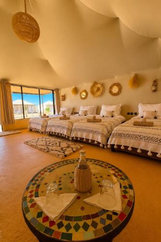 a large bedroom with three beds and a table at Aladdin merzouga camp in Merzouga