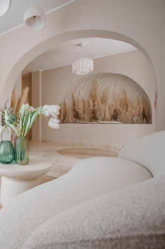 a white room with a bed and a vase of flowers at AMAREA BOUTIQUE Hotel in Eforie Sud