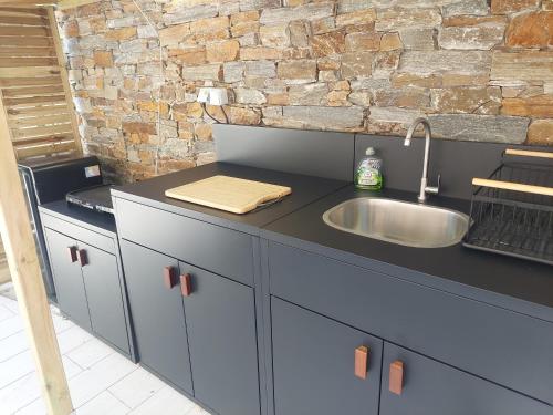 a kitchen with a sink and a brick wall at Chalet proche aéroport de Bastia in Lucciana