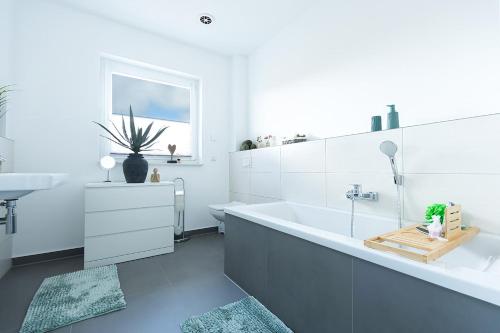 a white bathroom with a tub and a sink at Salz & Seele Das Spa Ferienhaus mit Whirlpool, Sauna & Wallbox in Büsum