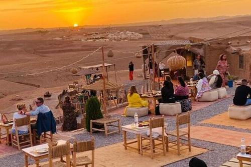 a group of people sitting around tables in the desert at Agafay Camping in Aït Daoud