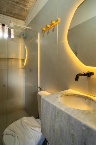 a bathroom with a sink and a mirror and a toilet at Pousada Varanda do Sol in Arraial d'Ajuda
