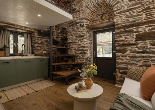 a kitchen and living room with a stone wall at Lithoskino Suites in Batsi