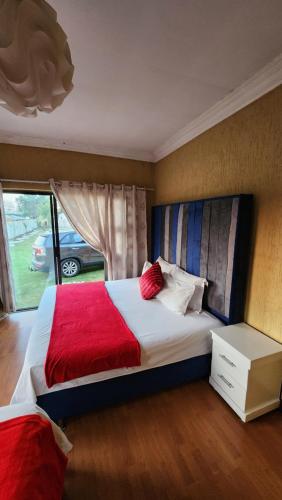 a bedroom with a large bed with a red blanket at Olympia GuestHouse in Kempton Park