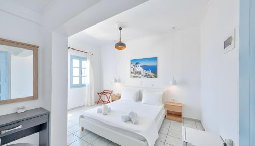 a white bedroom with a bed and a desk at Lume d'Oro Syros in Kini