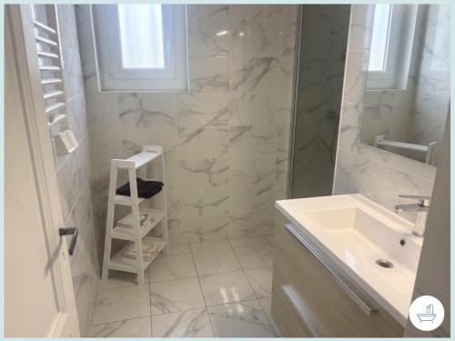 a white bathroom with a sink and a mirror at Le Jean Jaurès in Nîmes