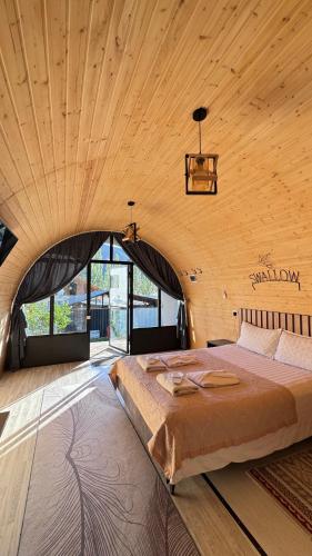 a large bed in a room with a wooden ceiling at Swallow in Karakol
