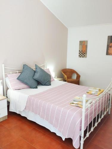 a bedroom with a white bed with pink and blue pillows at Casa dos Cavalos in Sertã