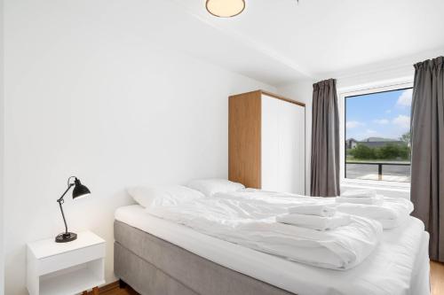 a white bedroom with a large bed with a window at Helt ny leilighet in Leknes