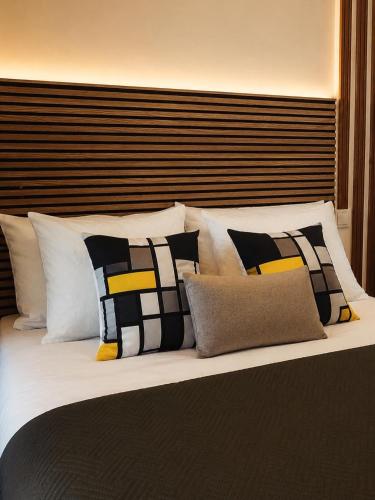 a large bed with many pillows on it at Kariokas Hospedagem in Águeda