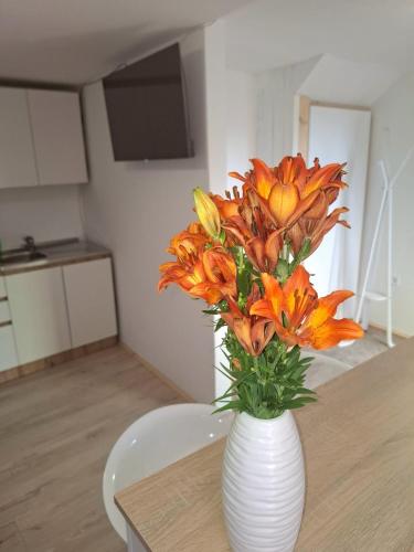 a white vase filled with orange flowers on a table at C&M Studio Apartment in Rijeka
