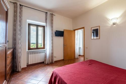 a bedroom with a red bed and a window at Appartamento BePlace - Subborgo in Rapolano Terme