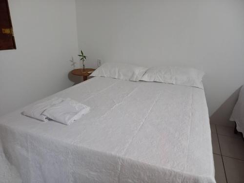 a white bed with white sheets and pillows on it at Villa Verde Chalés e Restô in Patos