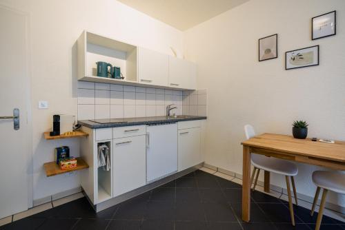 a kitchen with white cabinets and a wooden table at Gemütliches Studio im Stadtzentrum in Biel