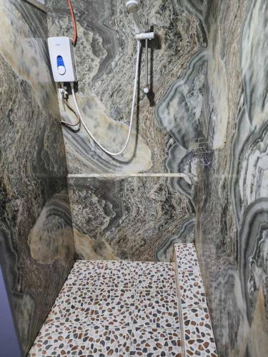 a stone bathroom with a shower and a rock wall at Aaqib Homestay in Suva