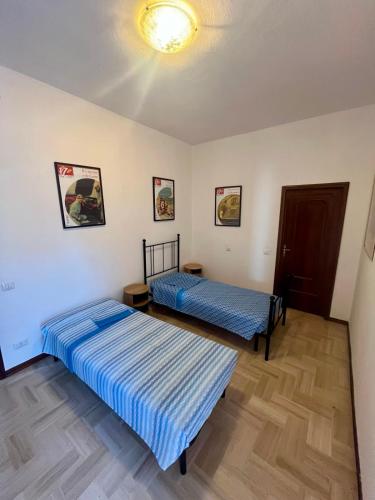 two beds in a room with blue sheets at Motor Rooms in Maranello