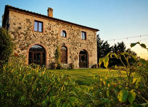 an old stone house on a grassy field at Il Cerchio delle Streghe Country House al Podere Casella in Castiglione dʼOrcia