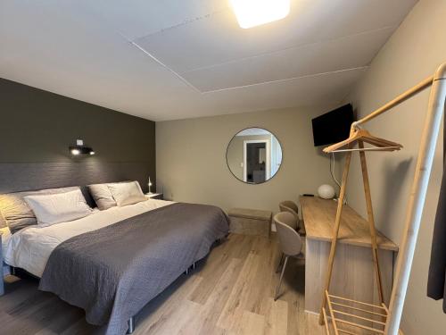 ein Schlafzimmer mit Bett, Spiegel und Schreibtisch in der Unterkunft Hotel De Villa in Zelzate