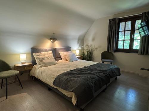 ein Schlafzimmer mit einem Bett, zwei Stühlen und zwei Fenstern in der Unterkunft Hotel De Villa in Zelzate