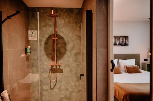 a shower with a glass door with a bed in a room at Hotel La Boutique in Nijmegen