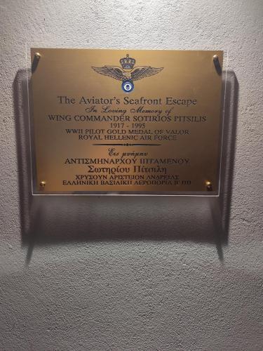 eine Gedenktafel an einer Wand mit einem Schild darauf in der Unterkunft Aviator's Seafront Escape in Ágios Nikólaos
