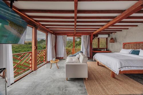 a bedroom with a bed and a couch and windows at Jaguar Beachfront Ecohotel & Spa in Santa Marta