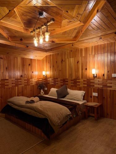 a bedroom with a large bed in a room with wooden walls at Avasaa Café and Stay in Jibhi