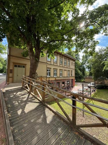 a wooden bridge in front of a building with a tree at Parka ielas apartamenti in Limbaži